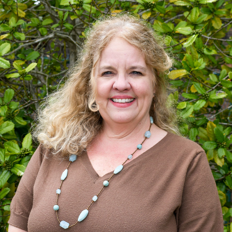 Portrait of Kimberly Blue, Sandhills Community College Title IX Coordinator, standing outdoors in front of green foliage.