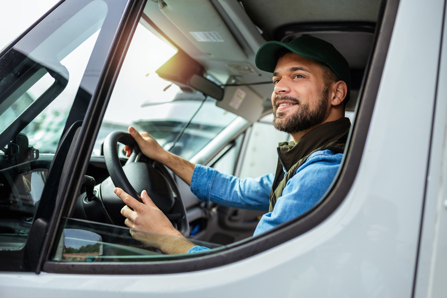 A delivery driver sits behind the wheel of a delivery truck, preparing to begin a route.