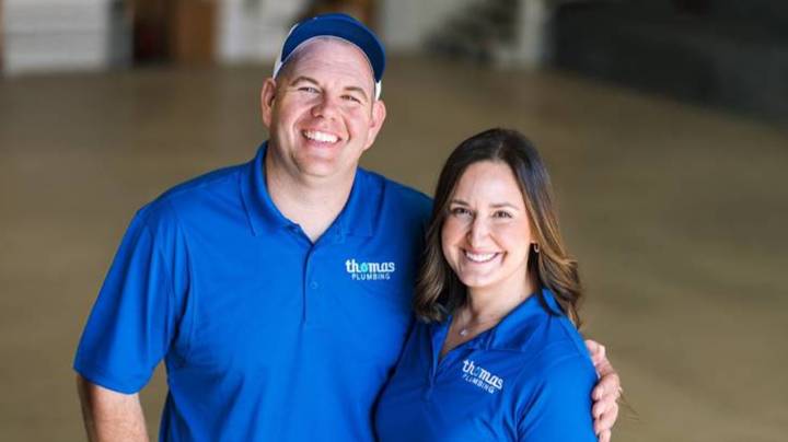 Thomas and Stephanie Mewherter, owners of Thomas Plumbing, standing together in blue Thomas Plumbing polo shirts