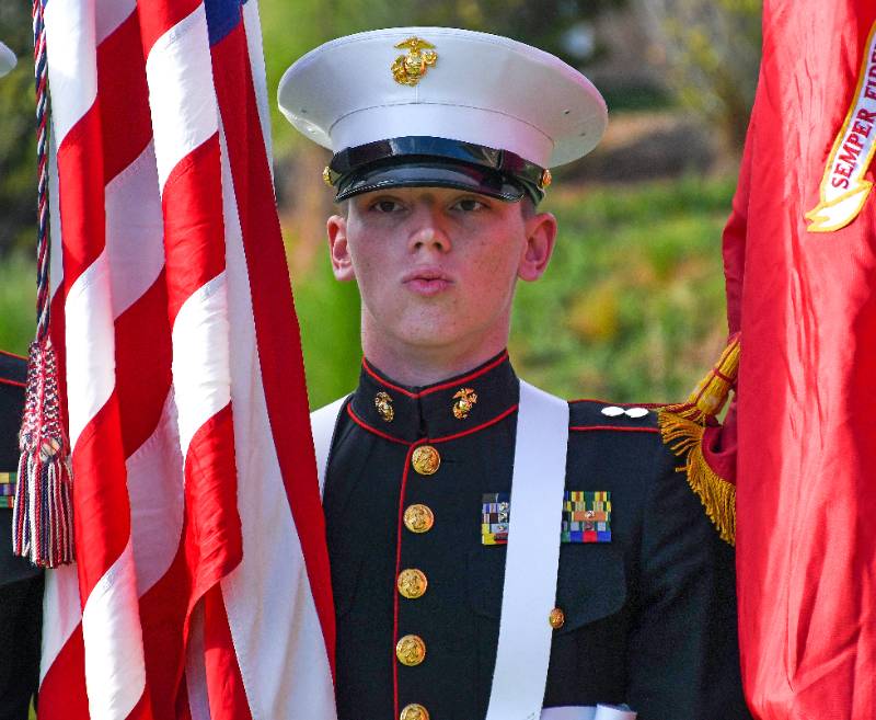 Marine JROTC cadet in full dress uniform stands at attention holding the American and Marine Corps flags during the Viking Drill Meet at Sandhills Community College.