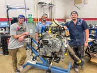 Sandhills Community College Collision Repair students stand beside the engine assembly of a donated Ford Escape while preparing it for conversion into a rehabilitation training vehicle.