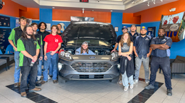 Sandhills Community College Collision Repair students pose around a 2021 Ford Escape inside the automotive shop as they prepare it for conversion into a rehabilitation training vehicle for The Lodge at Sandhills Carolina.