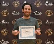 Matthew Celia – Student Awards Day Student Matthew Celia holding an award certificate and smiling in front of a Sandhills Community College Student Awards Day backdrop.