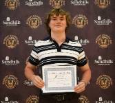 Ryan Watson – Student Awards Day Student Ryan Watson holding an award certificate and smiling in front of a Sandhills Community College Student Awards Day backdrop.