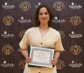 Student Zelma Mashburn holding an award certificate and smiling in front of a Sandhills Community College Student Awards Day backdrop. Zelma Mashburn – Student Awards Day