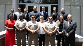Graduates of the Sandhills Community College Basic Law Enforcement Training program pose with instructors, staff, and supporters outside a campus building.