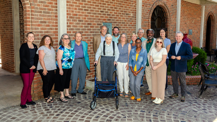 A group of Sandhills Community College leaders, employees, and community members gather for a photo outside a campus building.