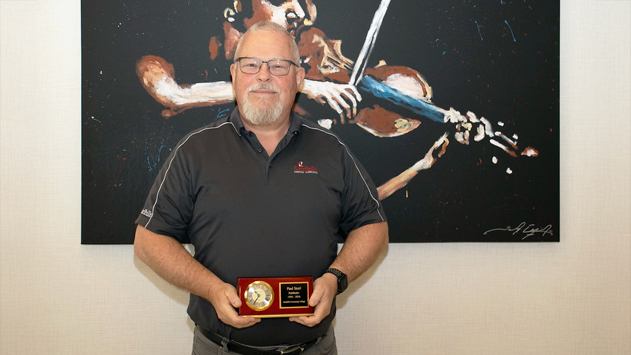 Paul Steele holds a retirement recognition award at Sandhills Community College.