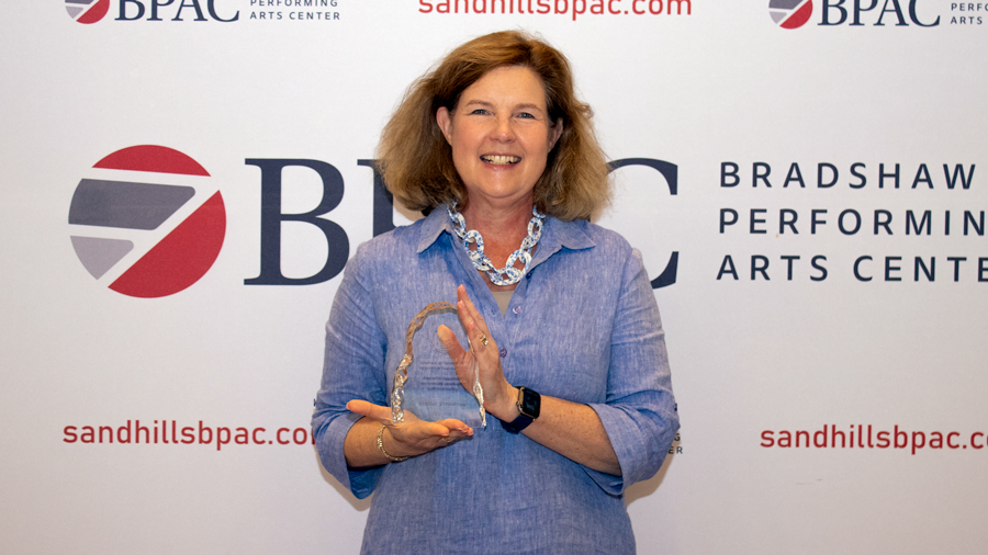 Sandhills Community College employee smiling while holding a glass award during the 2026 employee recognition ceremony.