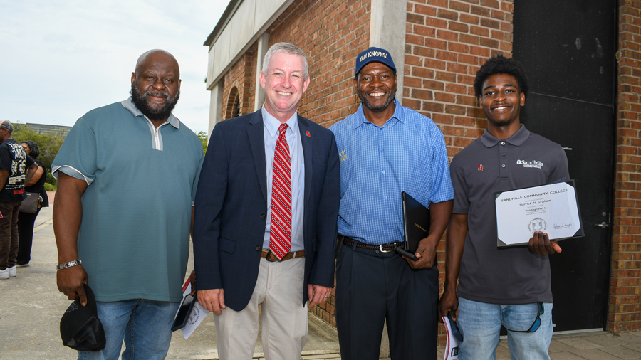 President Alexander “Sandy” Stewart poses with Workforce Continuing Education graduates and supporters following a Sandhills Community College graduation ceremony.