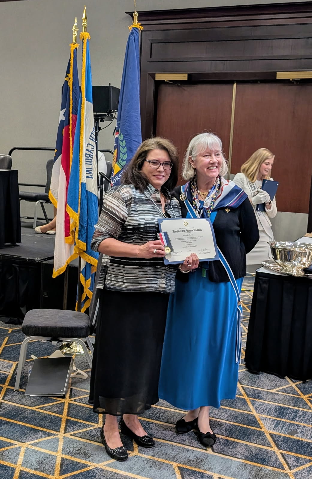 Maria Motta (left) receives national award from State Regent, Cricket Crigler at the 125th North Carolina DAR State Conference.