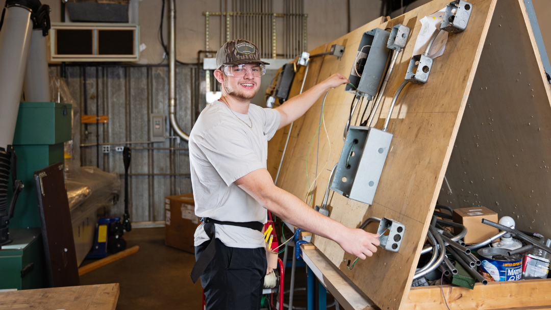 Pictured is a SCC electrical student working and smiling at the camera.